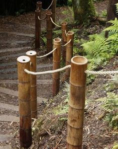 several wooden poles with ropes attached to them on the ground in front of some trees