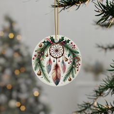 a ceramic ornament hanging from a christmas tree decorated with feathers and holly leaves