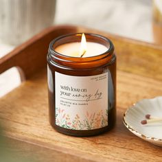 a candle sitting on top of a wooden table next to a plate with a spoon