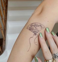 a woman's arm with a fan tattoo on the left side of her hand