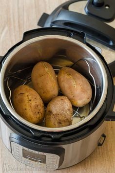 four potatoes in an electric pressure cooker on a wooden table with the lid open