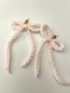 two pink crocheted hair ties on a white surface with gold hardware and beads