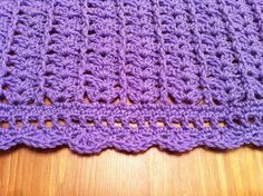 a purple crocheted blanket sitting on top of a wooden table