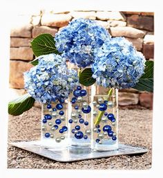 three vases filled with blue flowers on top of a table