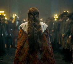 a woman with long hair standing in front of a group of people wearing medieval clothing