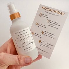 a hand holding up a bottle of room spray next to a card with information on it