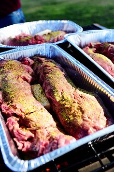 two trays filled with meat sitting on top of an open grill next to each other