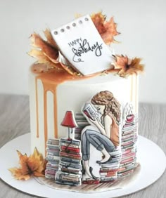 a cake decorated with books and an image of a woman sitting on top of it