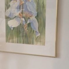 a painting hanging on the wall next to a vase with flowers in it and a cat