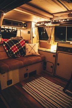 the inside of a camper is lit up with christmas lights and plaid throw pillows