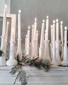 a group of white candles sitting on top of a mantle