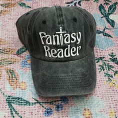 a black hat with the words fantasy reader on it sitting on top of a bed