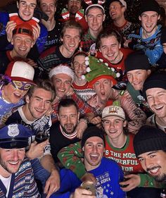 a group of men standing next to each other wearing ugly sweaters and christmas hats