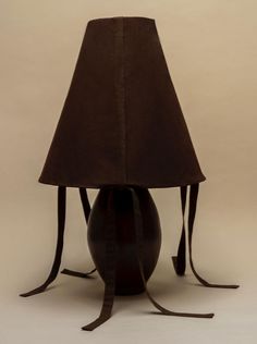 the lamp is shaped like a ball with ribbons on it's sides and has a dark brown shade