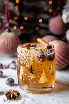 a glass filled with an alcoholic drink surrounded by christmas decorations