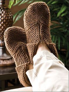 someone is wearing knitted slippers on their feet and they are sitting next to a pineapple