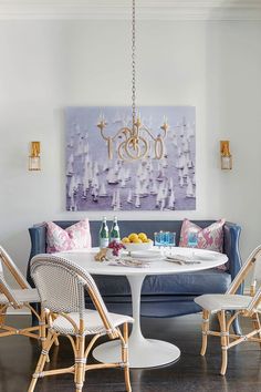 a dining room table with chairs around it and a painting on the wall behind it