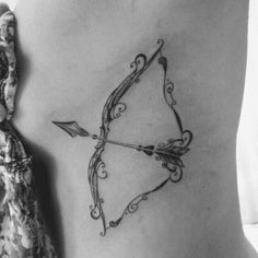 an arrow tattoo on the back of a woman's stomach