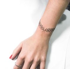 a woman's hand with a tattoo on her left wrist and an olive branch in the middle