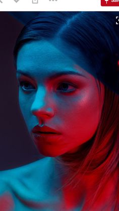 a woman with red and blue light on her face, looking at the camera while she is