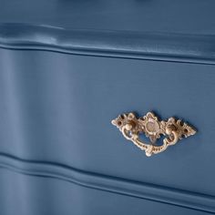 a blue dresser with an ornate brass handle