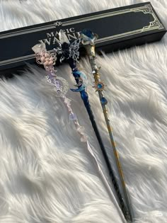 two long handled wands sitting on top of a white fur covered floor next to a black box