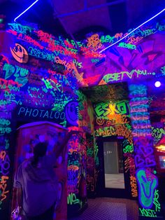 a woman standing in front of a wall covered in neon colors and writing on it