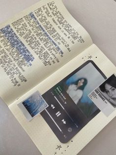 an open book with pictures and text on the pages is sitting next to a cell phone