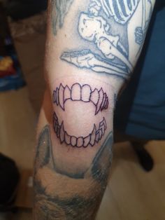 a man with a tattoo on his arm has a tooth and an image of a skeleton