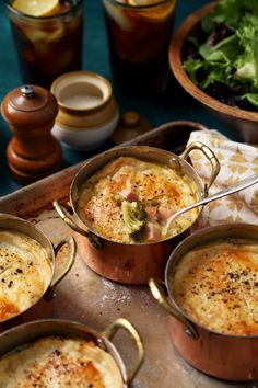 several pots filled with food sitting on top of a metal tray next to other dishes