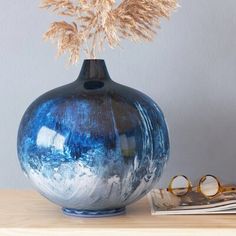 a blue vase sitting on top of a wooden table next to a pair of glasses