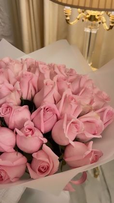 a bouquet of pink roses sitting on top of a table next to a lamp shade