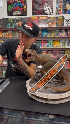 a man sitting at a table with a toy dinosaur on top of it in a store