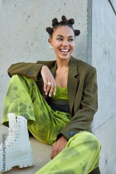 Stock Image: Positive carefree teenage girl with bun hairstyle looks happily away wears stylish green costume and white boots blue eyeliner feels good poses against grey concrete wall. Urban lifestyle concept Grey Concrete Wall, 70 Hairstyles, Bold Clothing, Green Costume, Green Costumes, Blue Eyeliner, Fashion Stand, Bun Hairstyle, Fashion Statements