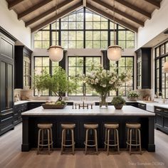 a large kitchen with black cabinets and an island in front of the windows that has flowers on it