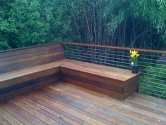 a wooden bench sitting on top of a wooden deck next to a planter filled with flowers