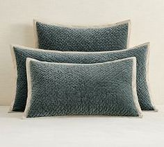 two blue pillows sitting on top of a white bed