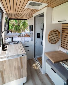 the interior of a camper with wood flooring and white walls, including a bed