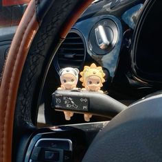 two cartoon figures sitting in the center console of a car next to a steering wheel