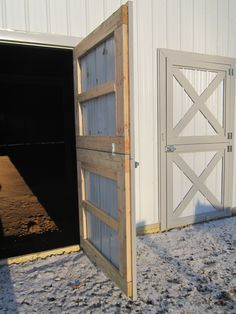 an open barn door in front of a white building