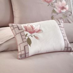 a bed with pink flowers on it and two pillows