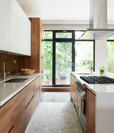 a kitchen with an oven, sink and stove top in front of a large window