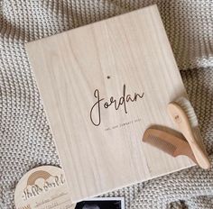 personalized wooden box with hairbrush, comb and postcard on the bed next to it