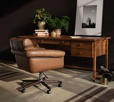 a brown leather office chair sitting in front of a desk with a plant on it