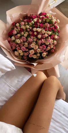 a woman laying on top of a bed holding a bouquet of flowers