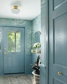 a blue front door with potted plants on the ledge and a mirror above it