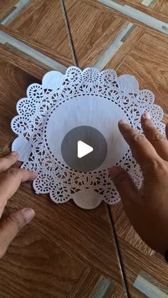 two hands are holding paper doily on the floor