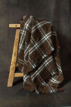 a blanket sitting on top of a wooden chair next to a black wall with a ladder