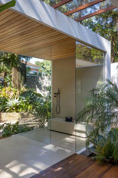 an outdoor shower in the middle of a wooden floored area with plants and trees