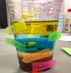 a cup filled with liquid sitting on top of a table next to a pile of sticky notes